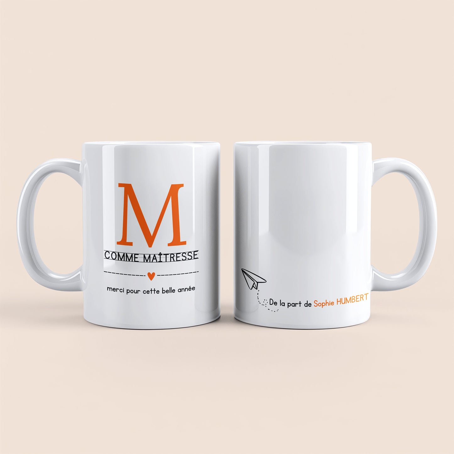 Mug blanc. Lettre M (maîtresse) et un cœur orange plus texte à gauche. Texte personnalisé avec nom à droite.
