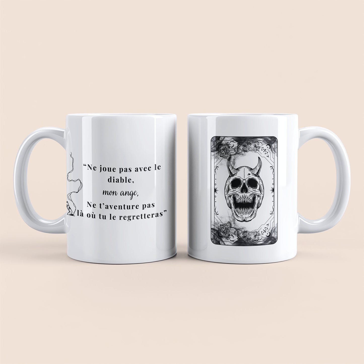 Mug blanc. Cigarette écrasée et Texte "Ne joue pas avec le diable mon ange. Ne t'aventure pas là où tu le regretteras" à gauche. Carte de jeux illustrant de la fumée et une tête de mort avec des cornes à droite.