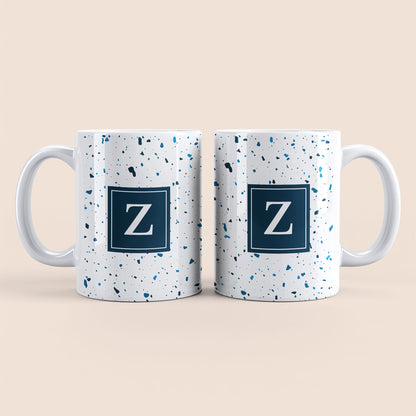 Mug blanc lettre personnalisé. Moucheté et avec un carré bleu au centre.