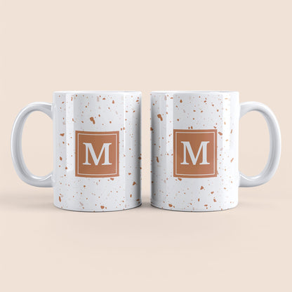Mug blanc lettre personnalisé. Moucheté et avec un carré marron clair au centre.