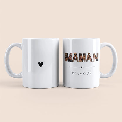 Mug blanc. Lettres "MAMAN" contenant des photos personnalisées et texte "d'amour" à droite. Cœur noir au centre à gauche.