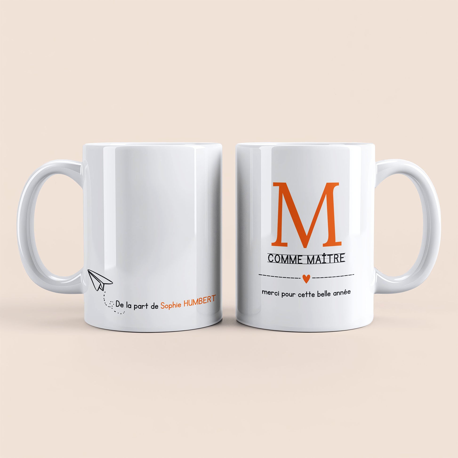 Mug blanc. Lettre M (maître) et un cœur orange plus texte à droite. Texte personnalisé avec nom à gauche.
