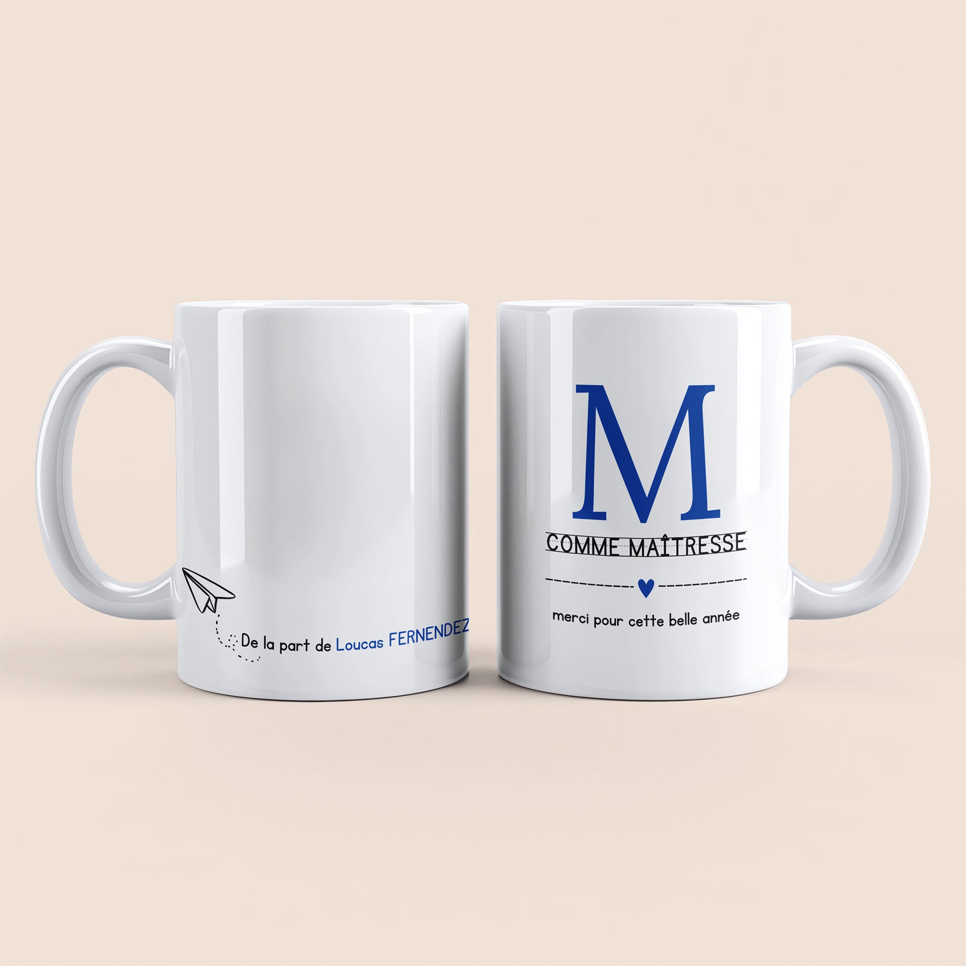 Mug blanc. Lettre M (maîtresse) et un cœur bleu plus texte à droite. Texte personnalisé avec nom à gauche.