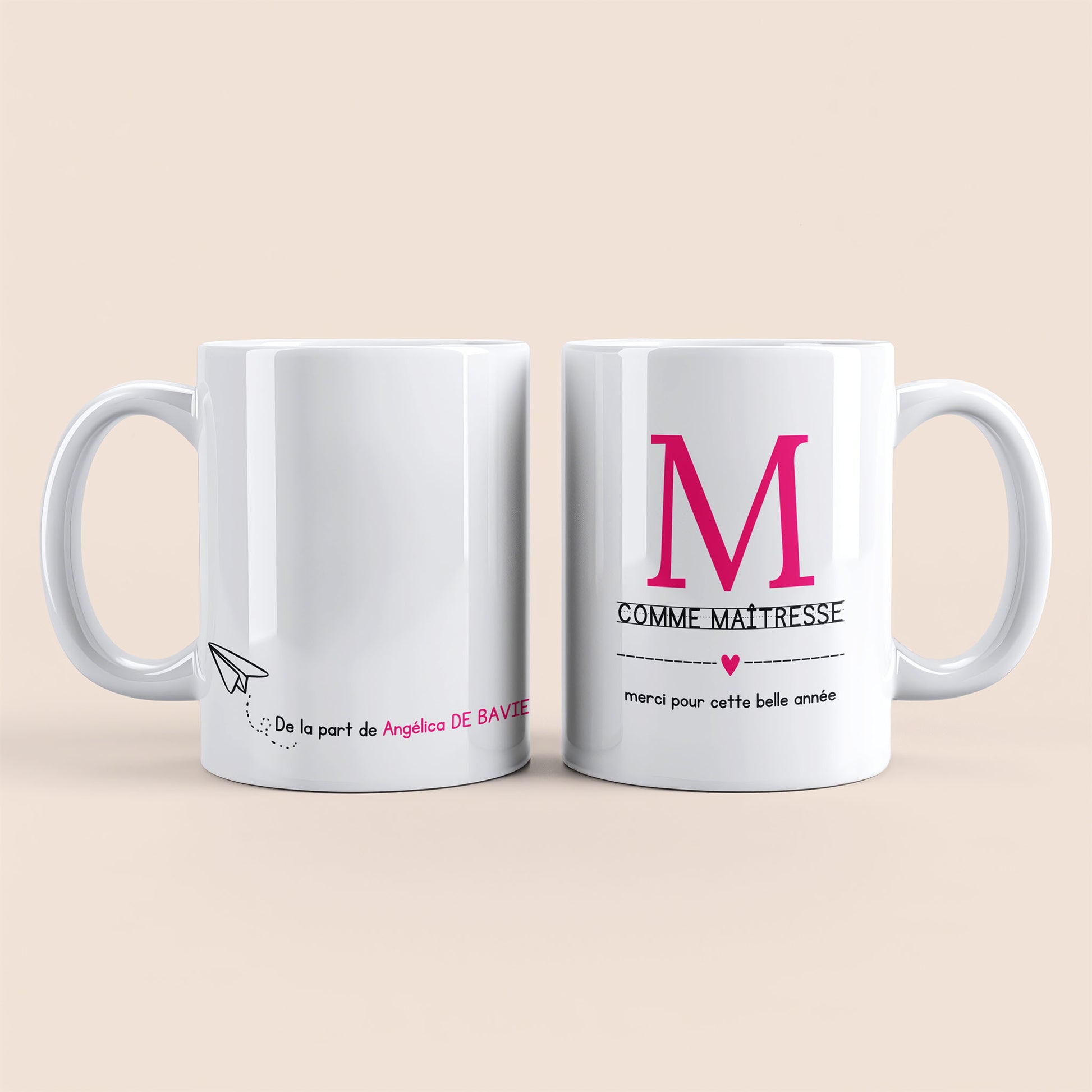 Mug blanc. Lettre M (maîtresse) et un cœur rose plus texte à droite. Texte personnalisé avec nom à gauche.