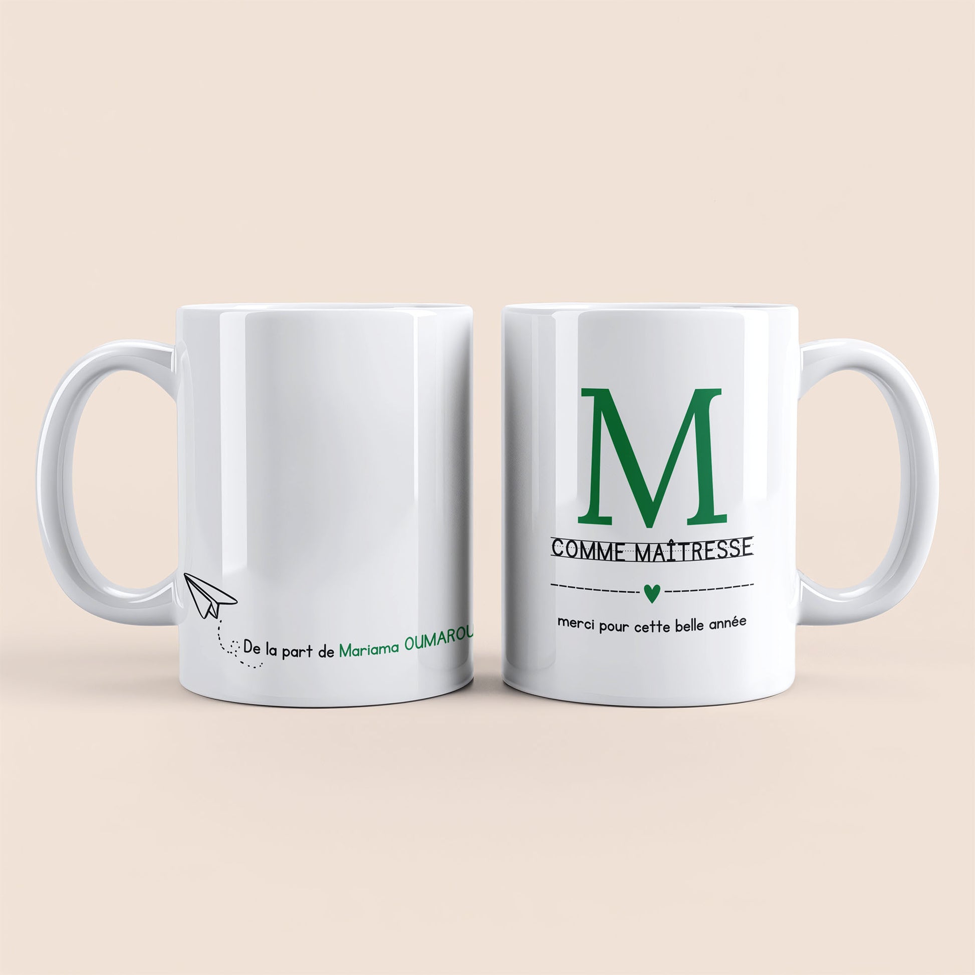 Mug blanc. Lettre M (maîtresse) et un cœur vert plus texte à droite. Texte personnalisé avec nom à gauche.