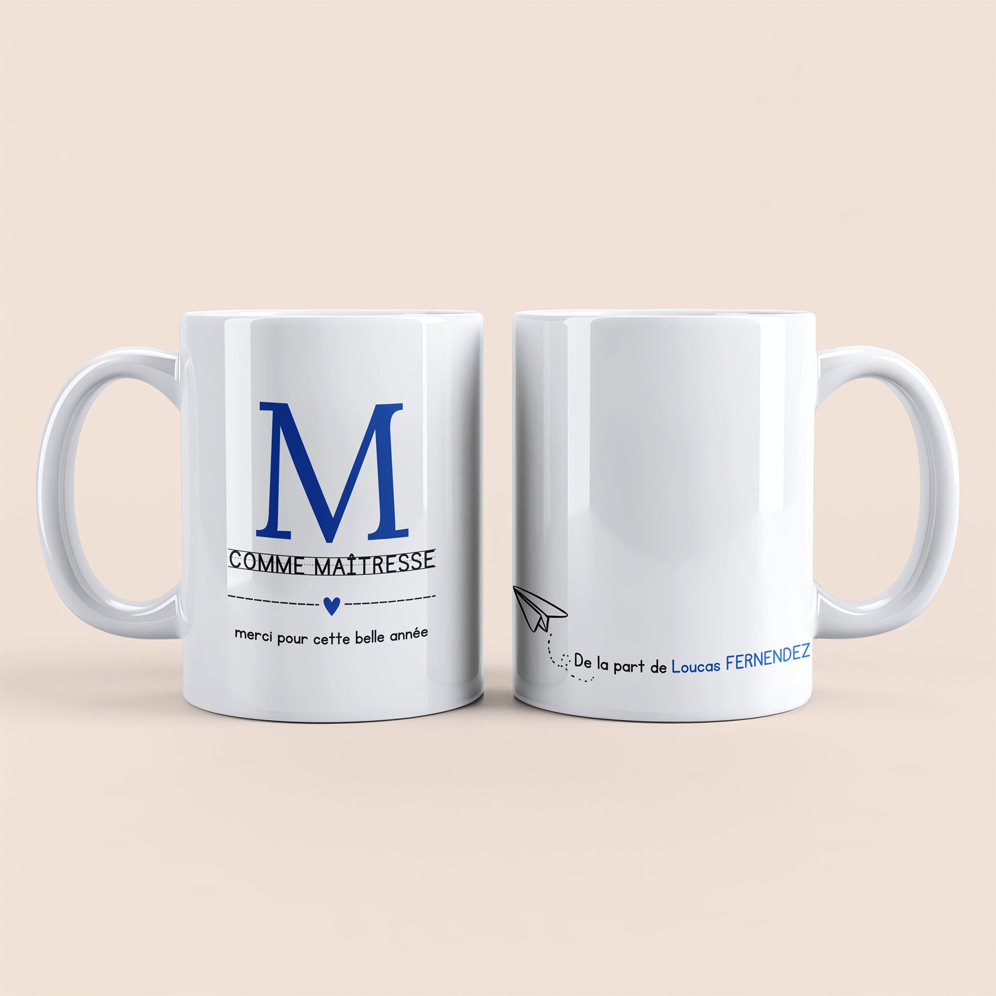 Mug blanc. Lettre M (maîtresse) et un cœur bleu plus texte à gauche. Texte personnalisé avec nom à droite.