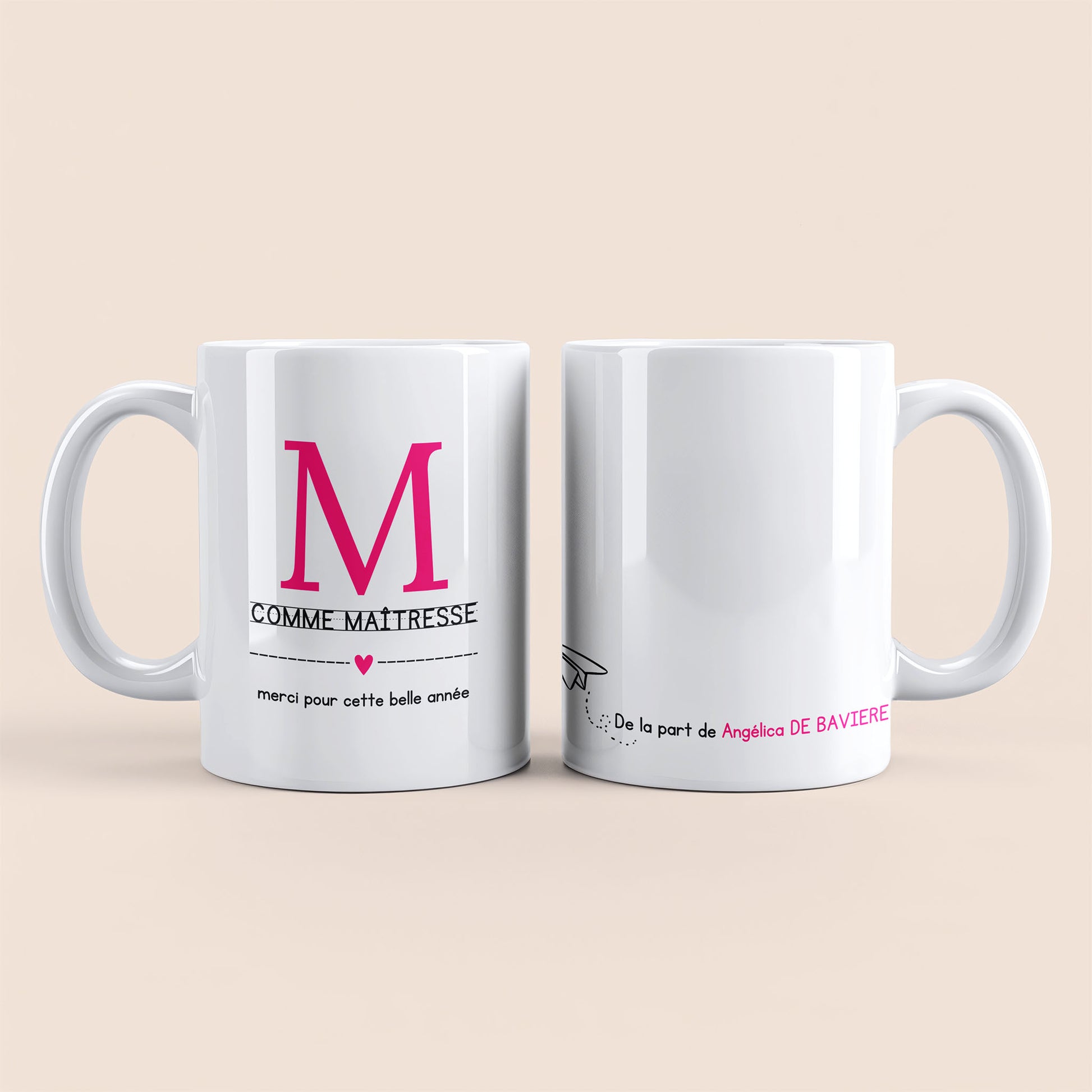Mug blanc. Lettre M (maîtresse) et un cœur rose plus texte à gauche. Texte personnalisé avec nom à droite.