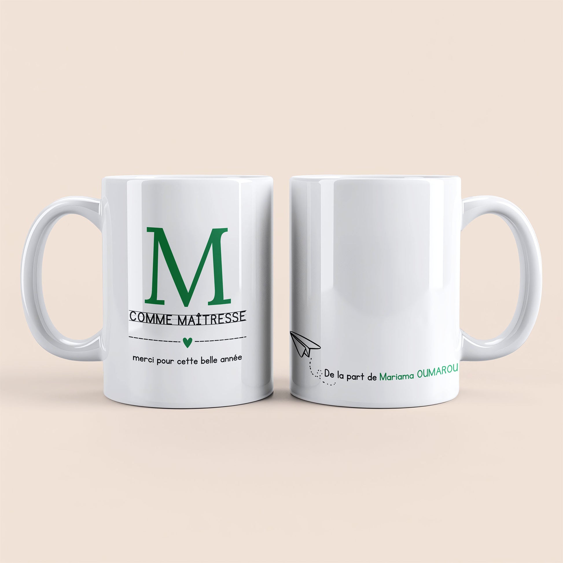 Mug blanc. Lettre M (maîtresse) et un cœur vert plus texte à gauche. Texte personnalisé avec nom à droite.